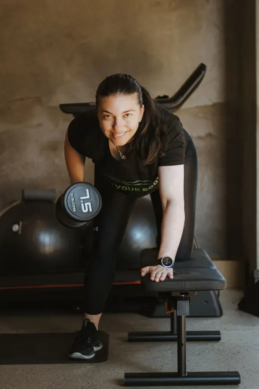Stephanie Francis coaching a one-on-one dumbbell row on a training bench in Bedfordview